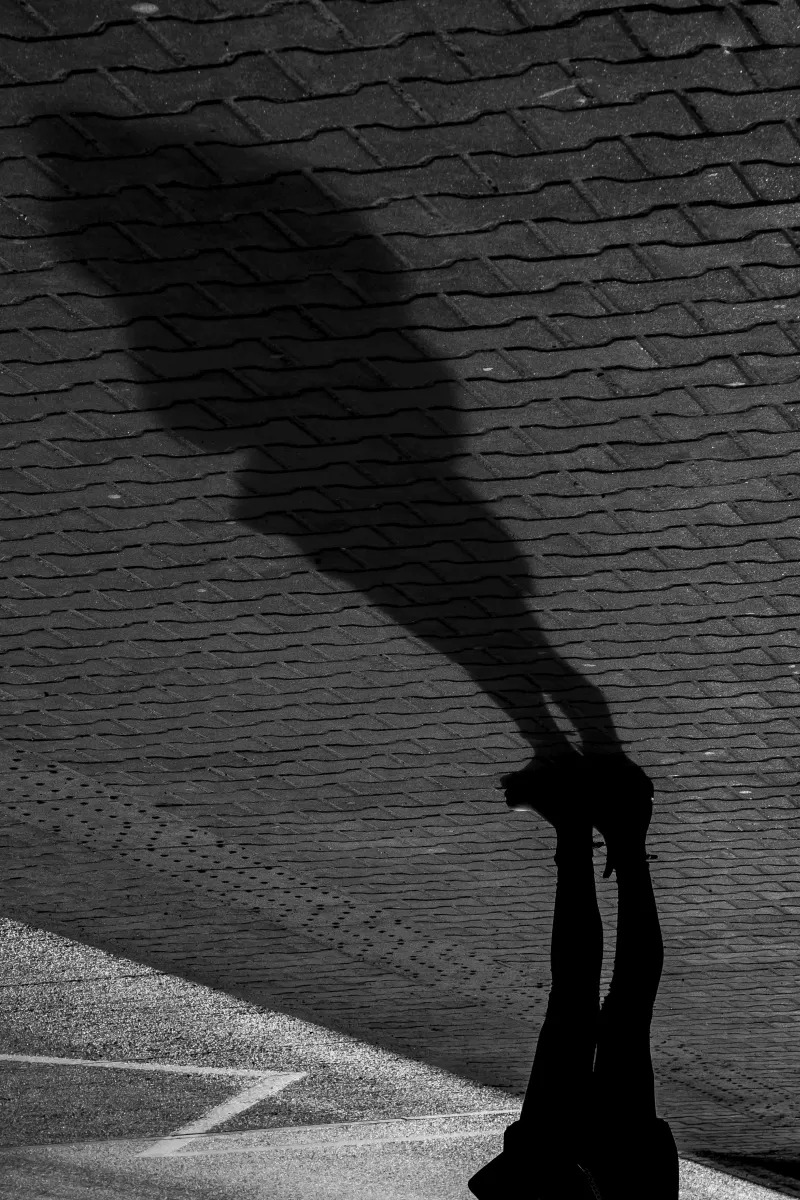 Long human shadow falling across rippled pavement